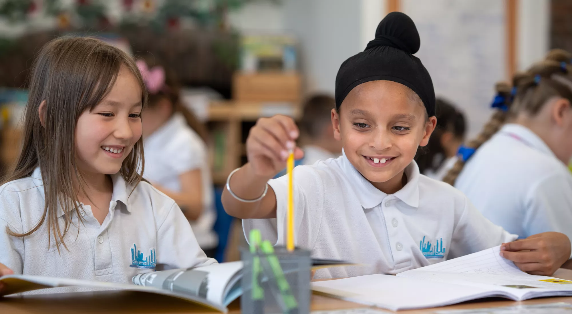 Two pupils at Canary Wharf Primary East Ferry enjoying a collaborative classroom learning activity.
